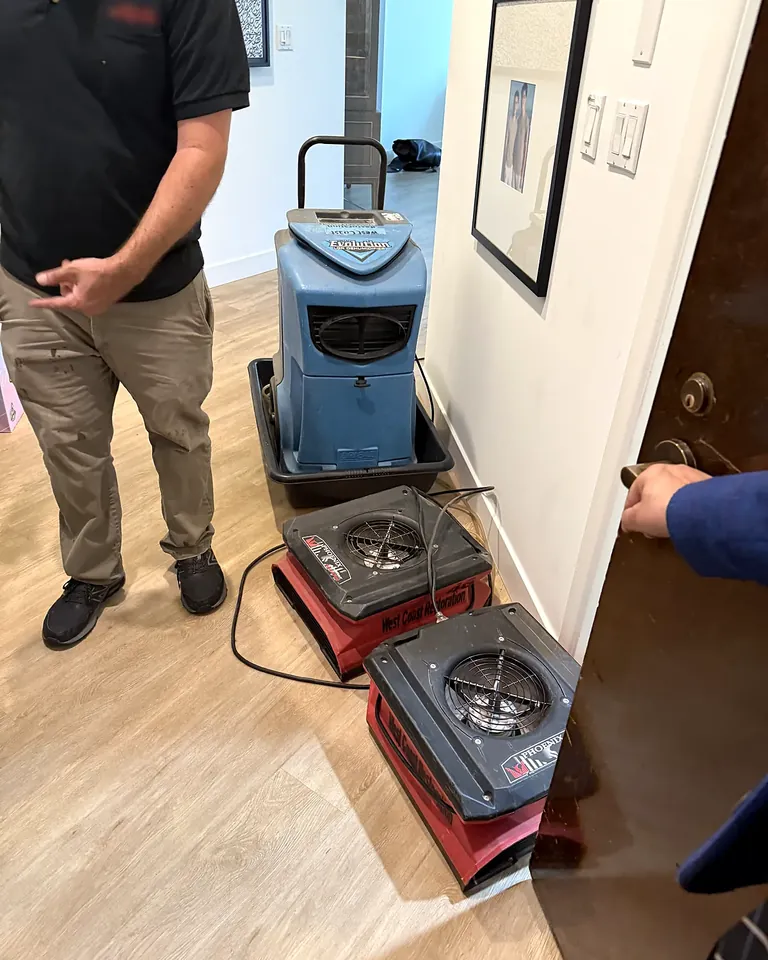 Technician setting up drying equipment in a commercial hallway