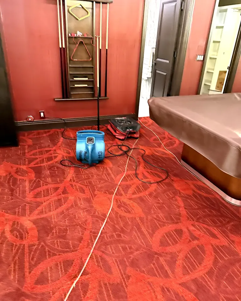 Air mover drying wet carpet in a game room
