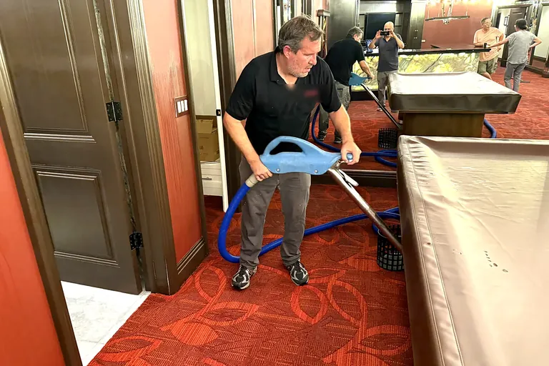 Technician extracting water from wet carpet in a flooded game room