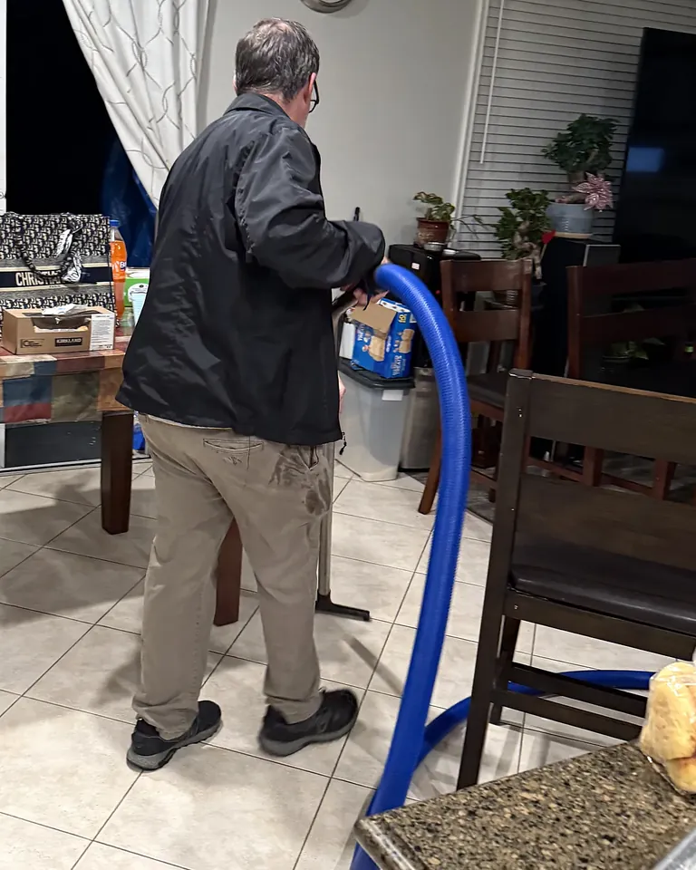 Technician removing standing water from a kitchen tile floor