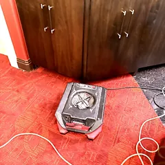 Air mover drying carpet beside built-in cabinets