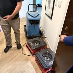 Technician setting up drying equipment in a commercial hallway
