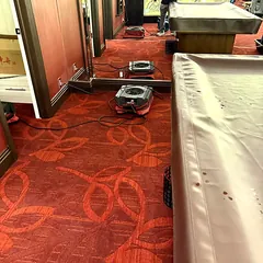 Air movers drying carpet along a game room