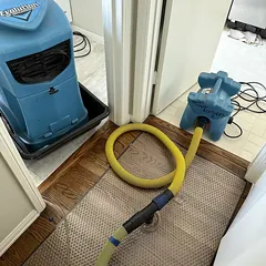 Dehumidifier and floor drying system on a water-damaged hardwood floor