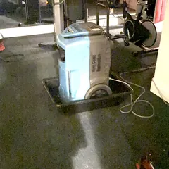 Dehumidifier drying a home gym after water damage
