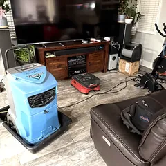 Commercial dehumidifier and air mover drying a living room floor