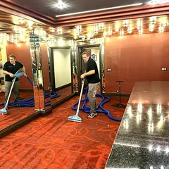 Two technicians running water extraction wands across a flooded carpet