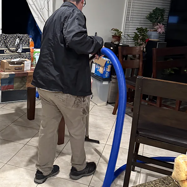 Technician removing standing water from a kitchen tile floor